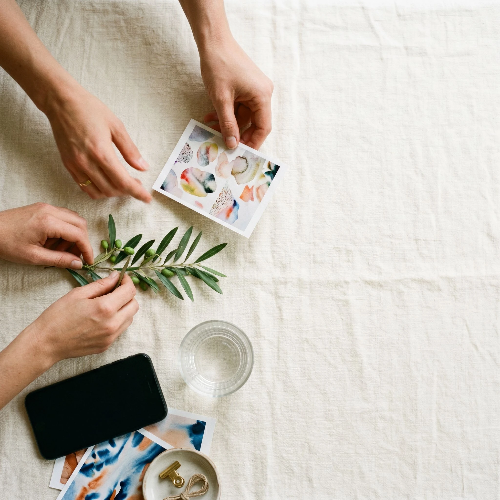 Top-down view of a social content shoot in progress with props, phone, and hands arranging objects on a light surface